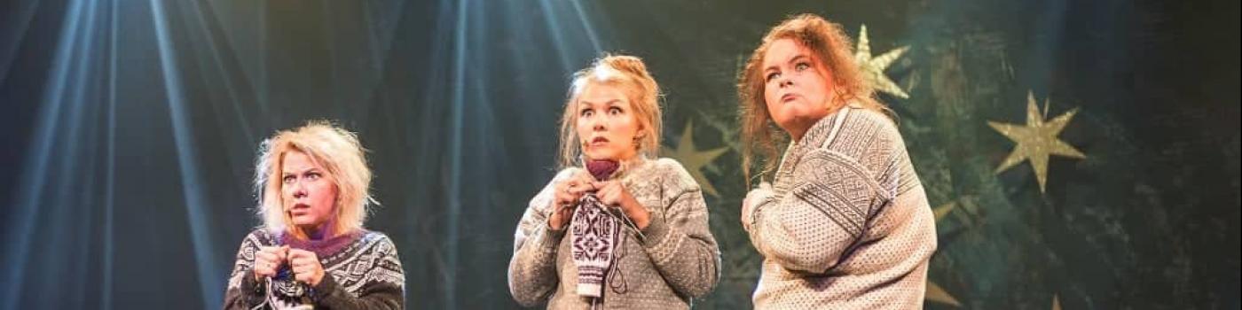 Tre damer på scena som strikker